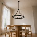 Low-angle dining room view | 8-light wagon-wheel chandelier over the round oak table