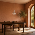 Terracotta dining room | clear seeded glass pendant over a dark wood table