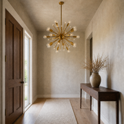 In a room | warm brass 24-light sphere chandelier in a greige entryway above a dark walnut console