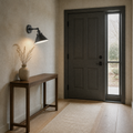 Entryway | matte black cone wall sconce beside a paneled door and tall sidelight