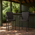 In a room | two dark brown woven wicker bar stools at a forest-green pavilion bar on a brick floor