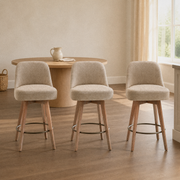 In a room | all three matching beige swivel counter stools at a plaster dining room's kitchen island edge, low golden afternoon light from the right