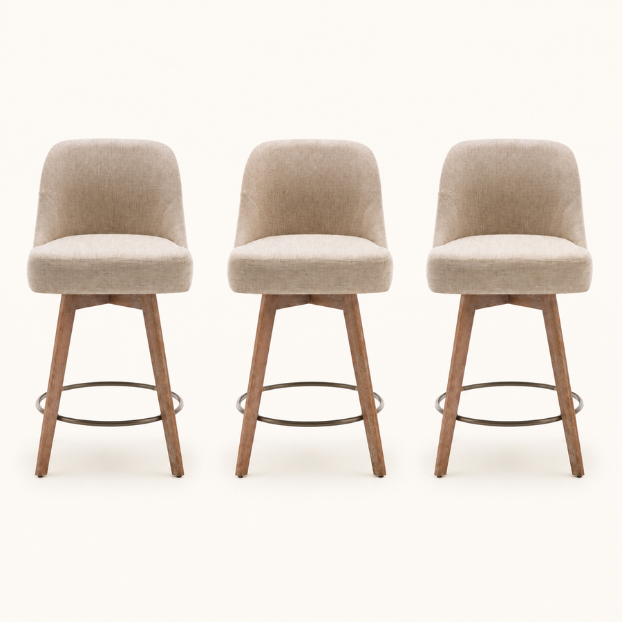 Front | all three matching beige swivel counter stools centered on paper, rounded backs and tapered wood legs with a bronze footrest ring