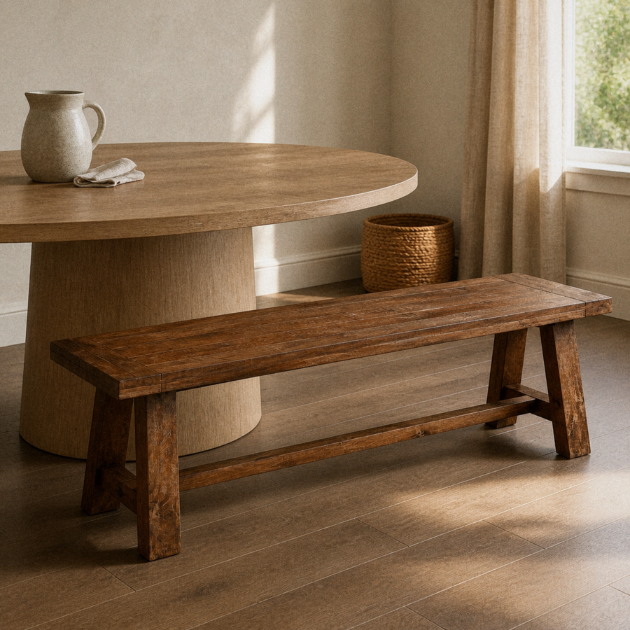 In a room | the same bench along a warm plaster dining room's round table, golden late-afternoon light from the right