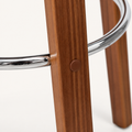 Detail | the polished chrome footrest ring where it meets the splayed wood legs