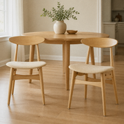 In a room | the pair beside a round table in a warm flax dining room, bright soft midday light