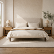 Room 1 | Straight-on view of the beige piped bed in a bright limewash bedroom with oak nightstands and a plain wool rug