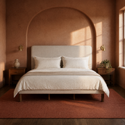 Room 2 | Straight-on view of the beige piped bed in a terracotta bedroom with walnut nightstands and brass lamps