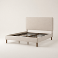 Studio three-quarter | Angled studio view of the beige upholstered bed with its low footboard and slat foundation