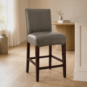 In a room | the stool at a bright flax dining room's island edge, midday light from the left