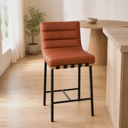 In a room | the stool at a pale-oak kitchen's island edge, soft morning sidelight from the left window