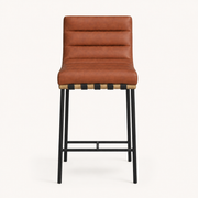 Front | cognac channel-tufted counter stool centered on paper, oak-veneer dowel rail with black straps and four matte-black legs