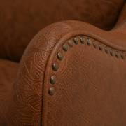 Hardware detail | dark round nailhead trim on the brown embossed faux-leather arm front