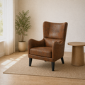 In a room | three-quarter view of the distressed brown embossed faux-leather wingback chair with side table and plant