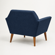 Studio side | rear-side view of deep navy basketweave armchair showing its plain outer back, side panel, and pecan birch legs