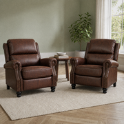Room | two reddish-brown distressed faux-leather push-back recliners with rolled arms, brass-tone nailhead trim and black turned bun feet on a plain oatmeal rug in a sage room