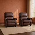 Room | two matching reddish-brown faux-leather push-back recliners on a plain oatmeal rug in a clay-walled room, with nailhead-trimmed rolled arms and black bun feet