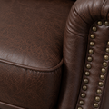 Texture close-up | reddish-brown distressed faux-leather upholstery with crackle grain, seam and rounded brass-tone nailhead trim