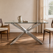 In a room | silver pedestal dining table with a clear glass top in an ivory plaster dining room, window at right