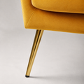 Hardware | close view of a tapered gold metal leg, black floor cap, and upholstered chair base