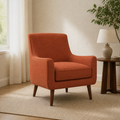 Reading room angle | Left three-quarter view of burnt-orange armchair with piped cushion and tapered wood legs