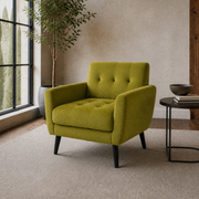 Angle | three-quarter view of an olive-green velvet armchair in the warm greige loft showing its seat side rail, square arms and black tapered legs