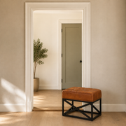 In scale | saddle tan leather ottoman beside a full-height interior doorway