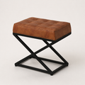 Three-quarter | rectangular saddle tan leather ottoman showing its stitched top, leather side, and black X-base