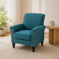 Oak living room three-quarter | blue-green tweed nailhead armchair on a plain rug beside a pale wood table