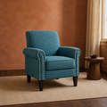 Clay living room | blue-green tweed nailhead armchair on a plain rug beside a walnut pedestal table