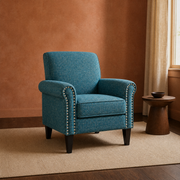 Clay living room | blue-green tweed nailhead armchair on a plain rug beside a walnut pedestal table