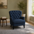 In a room | navy blue tufted chair in a sage green room with a window, side table, plant, and gray rug