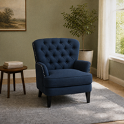 In a room | navy blue tufted chair in a sage green room with a window, side table, plant, and gray rug