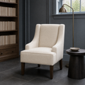Cool library room | cream swoop-arm chair in blue-gray millwork with a brass floor lamp