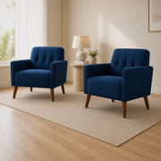 Set complete | two deep blue tufted armchairs in a warm ivory room from a low opposite three-quarter angle
