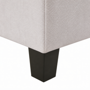 Hardware | close view of a dark solid-wood block foot beneath the ivory upholstery corner and side seam