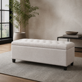 Room 3 | Ivory button-tufted storage bench in a taupe room with a black-framed window, leafy plant, black console, and plain gray rug