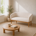 Angle | three-quarter reading-room view of the beige channel-back loveseat and round oak table