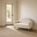 Scale in an entry | Cream textured loveseat beside a full-height glass-panel door in a neutral entry room