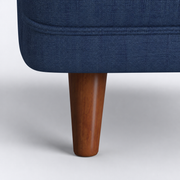 Component close-up | espresso-finish tapered pine leg where it meets the navy upholstered base