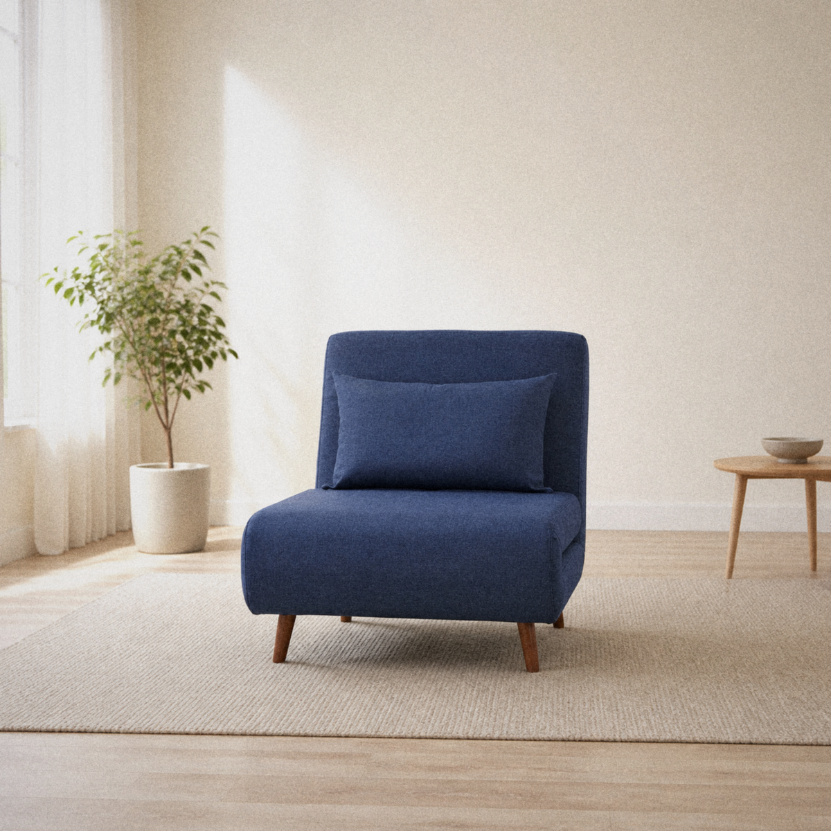Room 1 | navy blue armless convertible chair on a plain oatmeal rug in a warm white room with a window at left