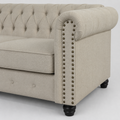 Detail | Close view of the bronze nailhead trim along a rolled beige linen-blend arm