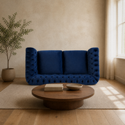Room | Navy-blue velvet button-tufted rolled-arm loveseat in a warm sand living room with a walnut coffee table and oatmeal rug