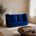 Angle | Three-quarter view of the navy-blue button-tufted rolled-arm loveseat in the warm sand living room