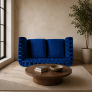 Room | Navy-blue velvet button-tufted rolled-arm loveseat in a warm stone living room with a dark-oak coffee table
