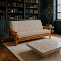 Room | Linen stone futon in a deep blue-green library with herringbone floor, bookshelves, brass lamp and cream rug
