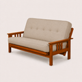 Studio | Linen stone futon from a 55-degree front-right angle, showing the full seat, piping, frame rails and both slatted arms