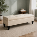 Sage living room angle | Beige button-tufted storage bench with low side table and leafy plant