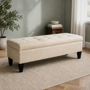 Sage living room angle | Beige button-tufted storage bench with low side table and leafy plant