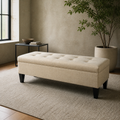 Loft reading room | Beige button-tufted storage bench on a plain stone rug by black-framed window